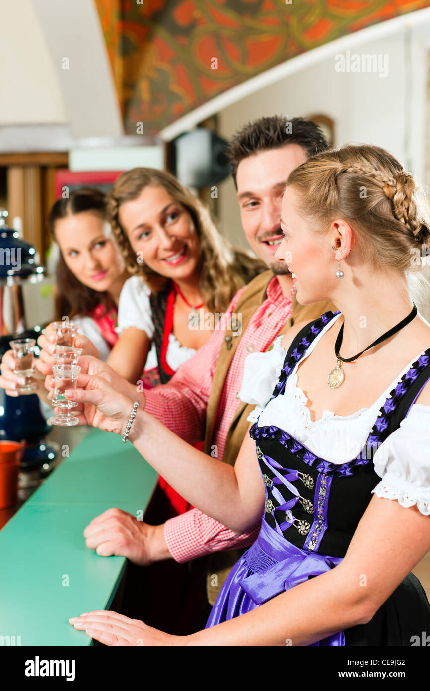 Persone in Baviera Tracht bere liquore duro in un pub e divertirsi Foto Stock