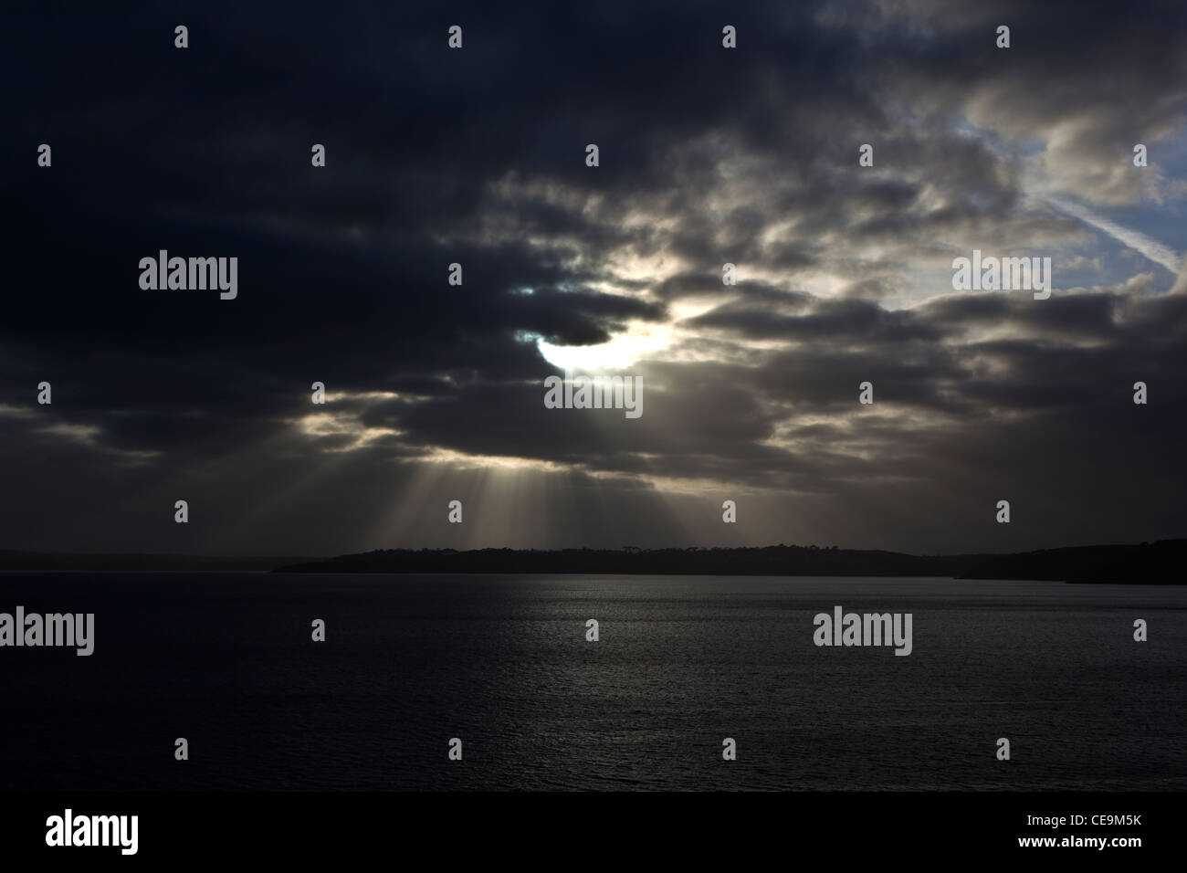 Un burst di cloud attraverso una drammatica moody sky a Falmouth Bay oltre la penisola di Lizard. Foto Stock