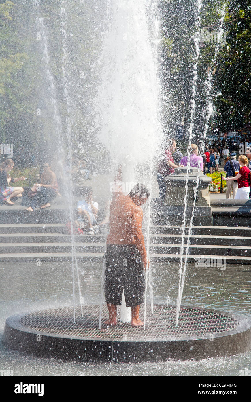 Un uomo gli schizzi nella fontana di acqua a Washington Square Park a Manhattan, New York City. Foto Stock