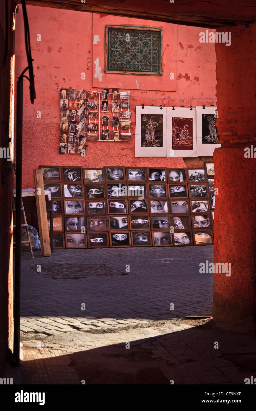 Guardando attraverso una porta su una parete rosa con foto di donne velate, Marrakech, Marocco Foto Stock