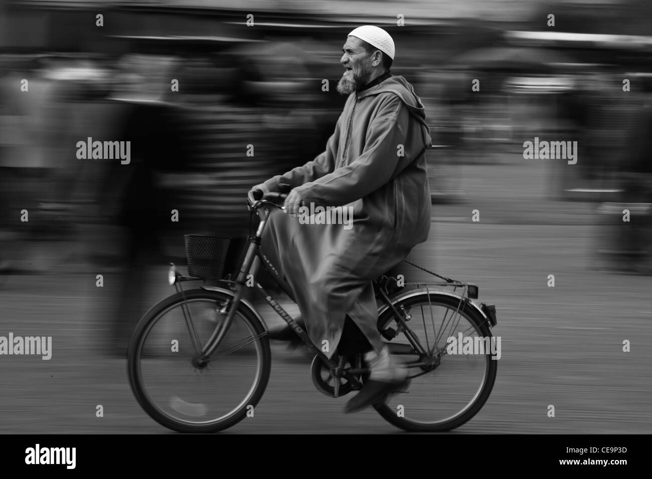 Un uomo che cavalca la sua bicicletta attraverso Marrakech, Marocco Foto Stock