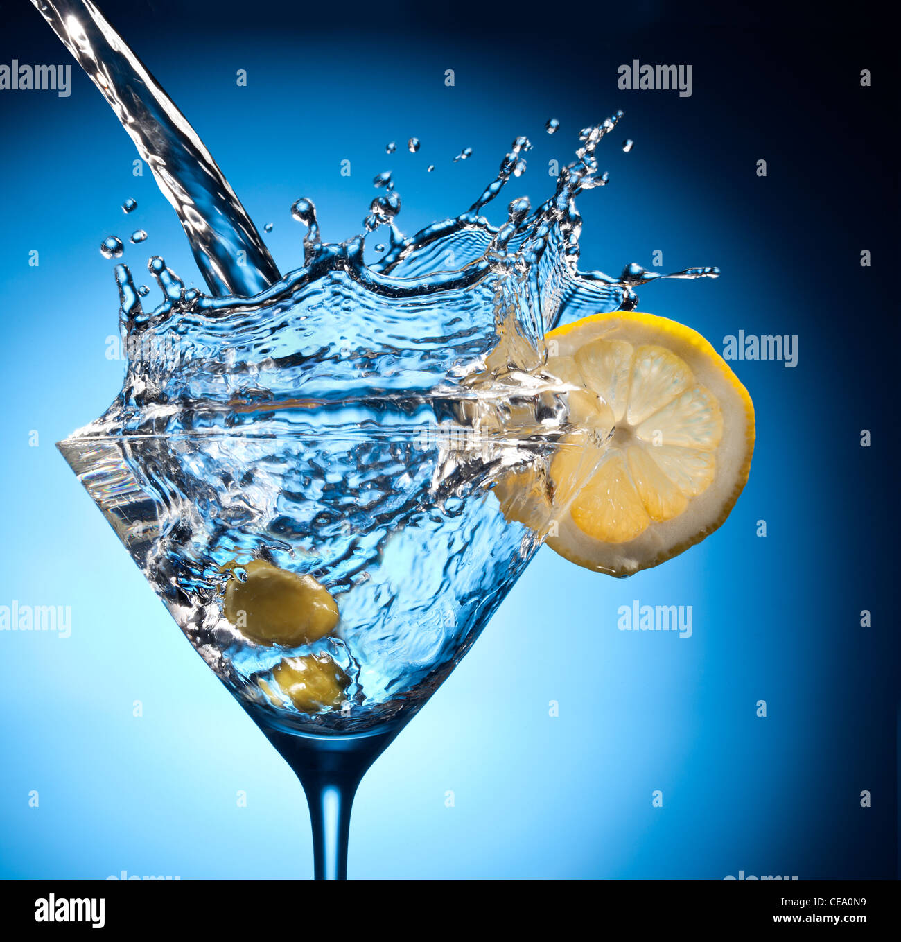 Splash dal colaggio martini in vetro. Oggetto su uno sfondo blu. Foto Stock