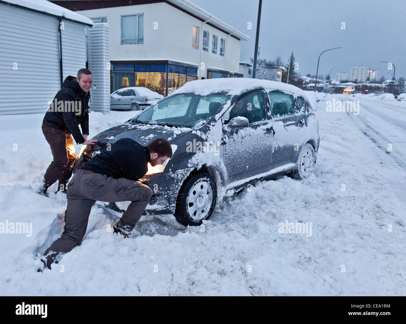 Spingendo un filamento auto dopo una tempesta di neve, Reykjavik Islanda Foto Stock