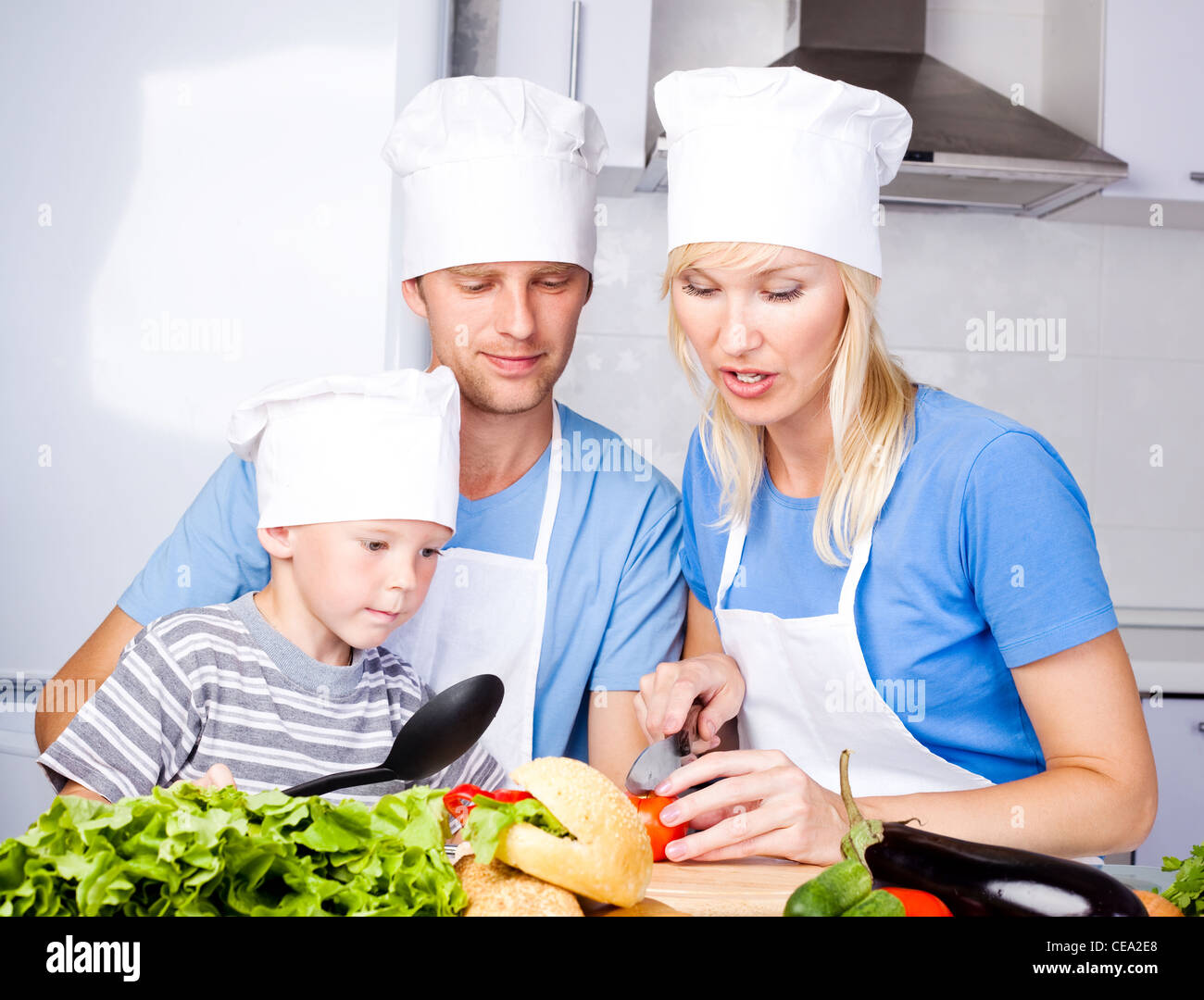 Famiglia giovane; padre, madre e i loro cinque anno vecchio figlio cucinare insieme in cucina a casa Foto Stock
