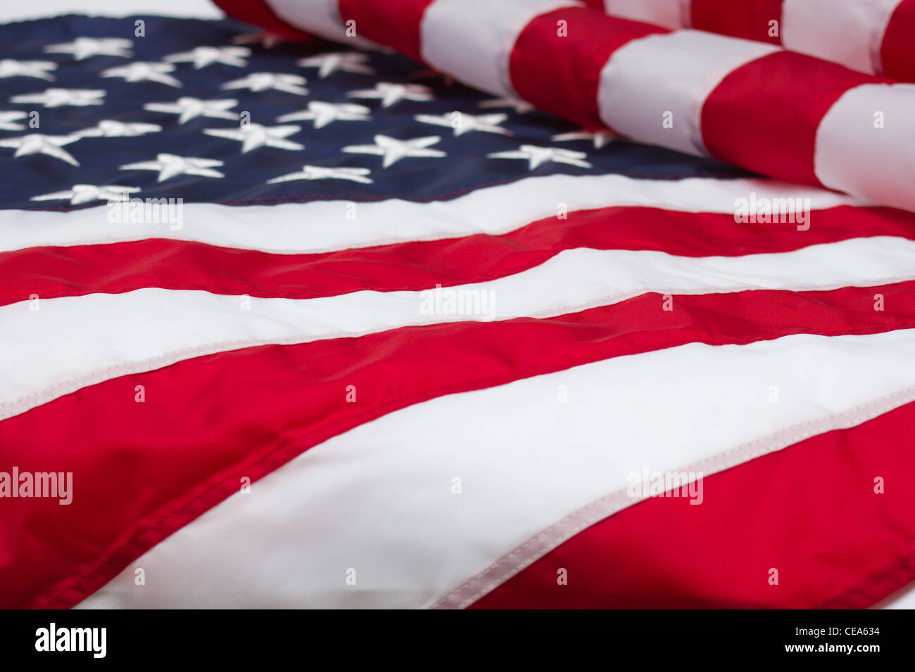 Un parzialmente piegato bandiera americana con le stelle leggermente fuori fuoco e le strisce in una messa a fuoco nitida in primo piano. Foto Stock