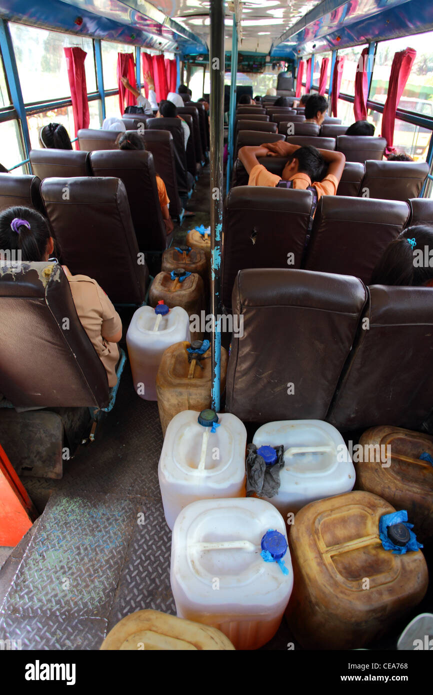 Gli allievi su un bus caricato con contenitori di plastica di kerosene. Il nord di Sumatra, Indonesia, Asia sud-orientale, Asia Foto Stock