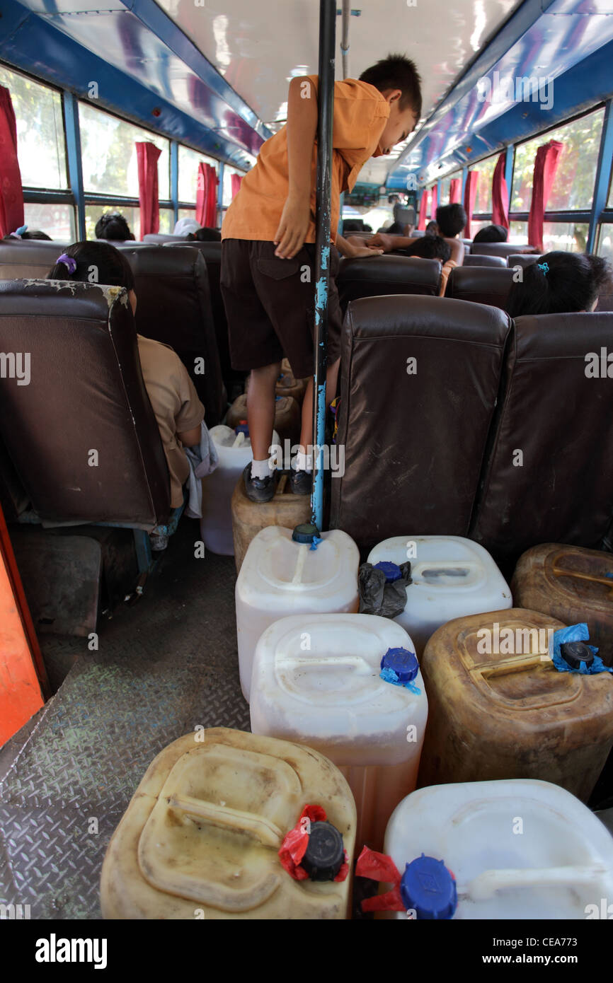 Gli allievi su un bus caricato con contenitori di plastica di kerosene. Tangkahan, nel nord di Sumatra, Indonesia, Asia sud-orientale, Asia Foto Stock