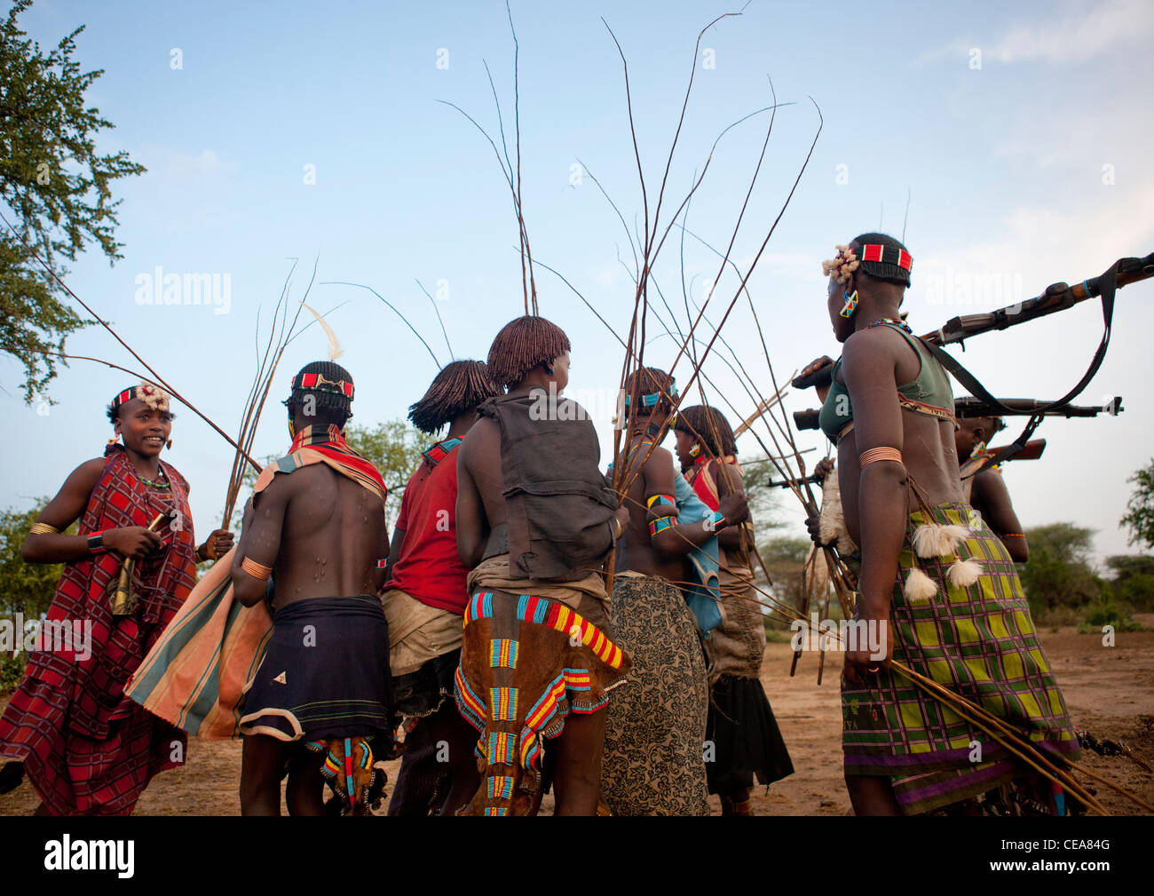 Le donne a piedi con fruste e Kalashnikov a Bull Jumping cerimonia Etiopia Foto Stock