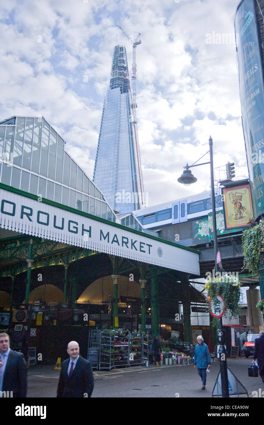 La Shard costruzione costruzione di gru giganti che domina il mercato di Borough sign & canopy & nuovo ponte del treno per la stazione di London Bridge Street scene Foto Stock
