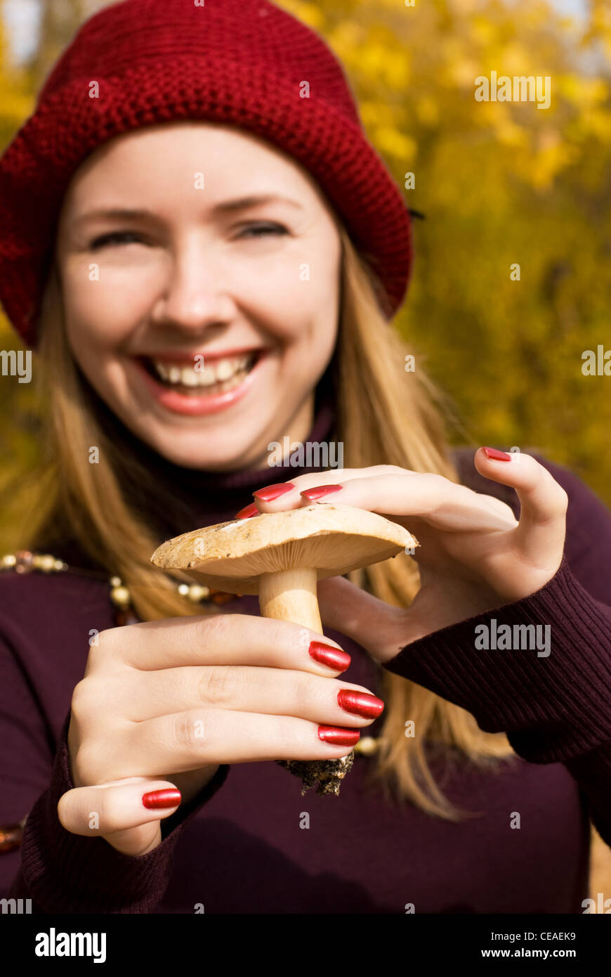 Sorridenti ragazza bionda che mostra il fungo ha appena trovato nella foresta Foto Stock