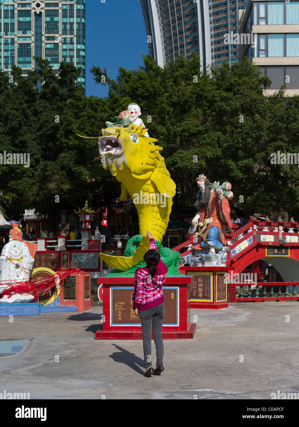 Dh REPULSE BAY HONG KONG ragazza cinese di buttare soldi nel pesce della prosperità statua bocca Foto Stock