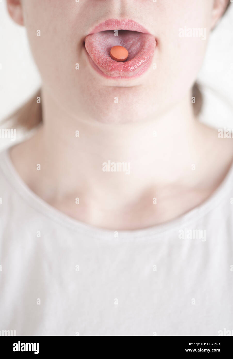 Donna con una pillola sulla sua lingua Foto Stock