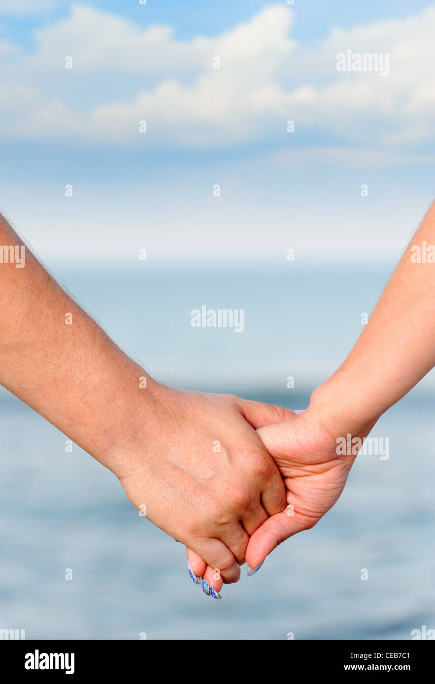 L uomo e la donna a tenere per le mani. Contro il mare e il cielo Foto Stock