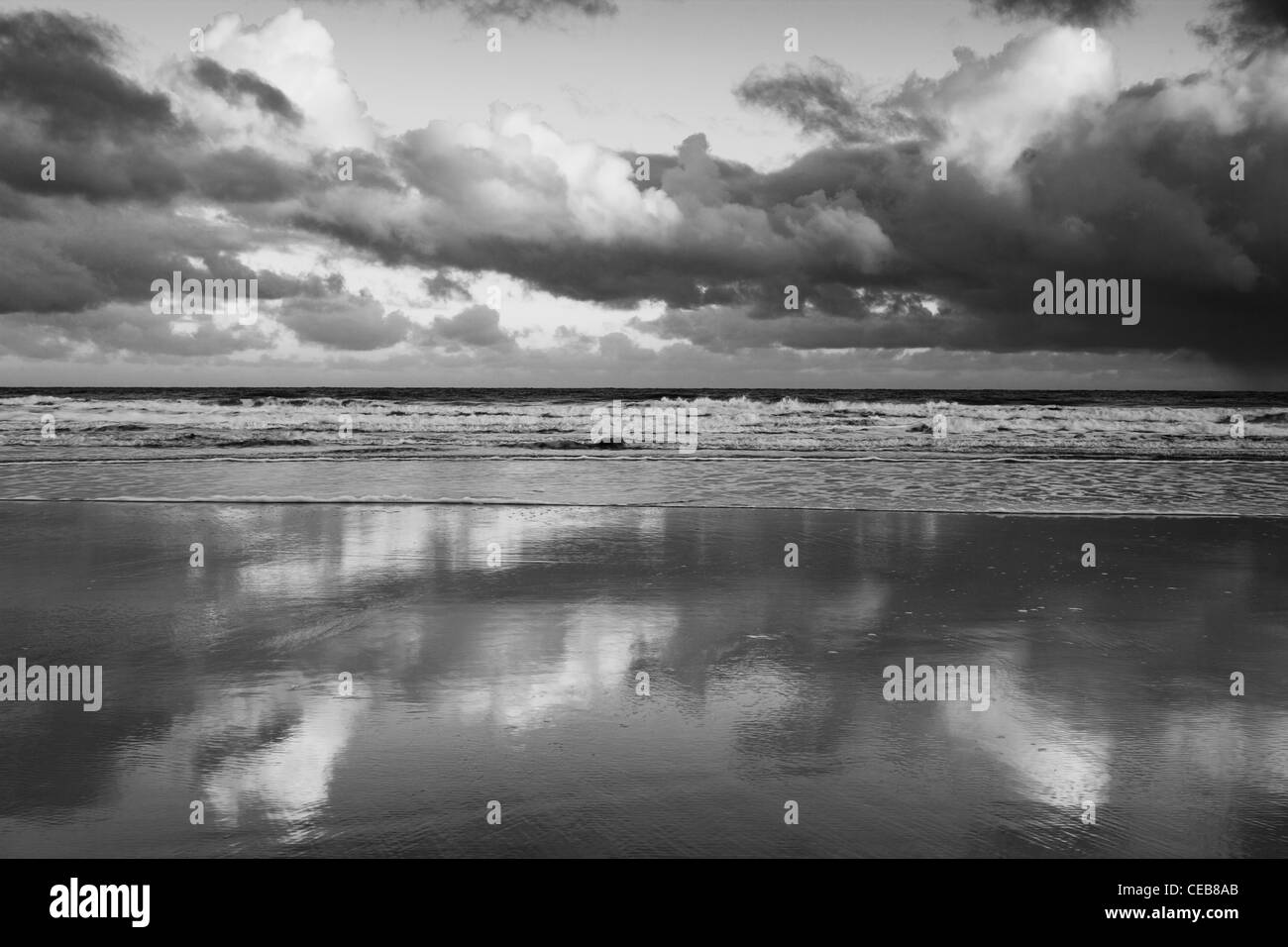 Soleggiato nuvole riflettono nella sabbia bagnata sulla spiaggia Bamburgh. Foto Stock