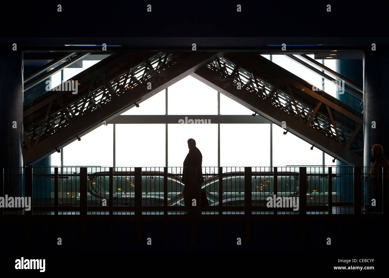 Una silhouette di un gentiluomo senior in un centro commerciale per lo shopping con un cielo luminoso dietro di lui. Foto Stock