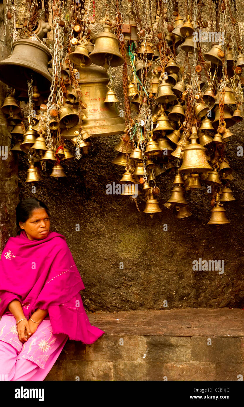 Una signora in appoggio sotto campane di un tempio, India Foto Stock