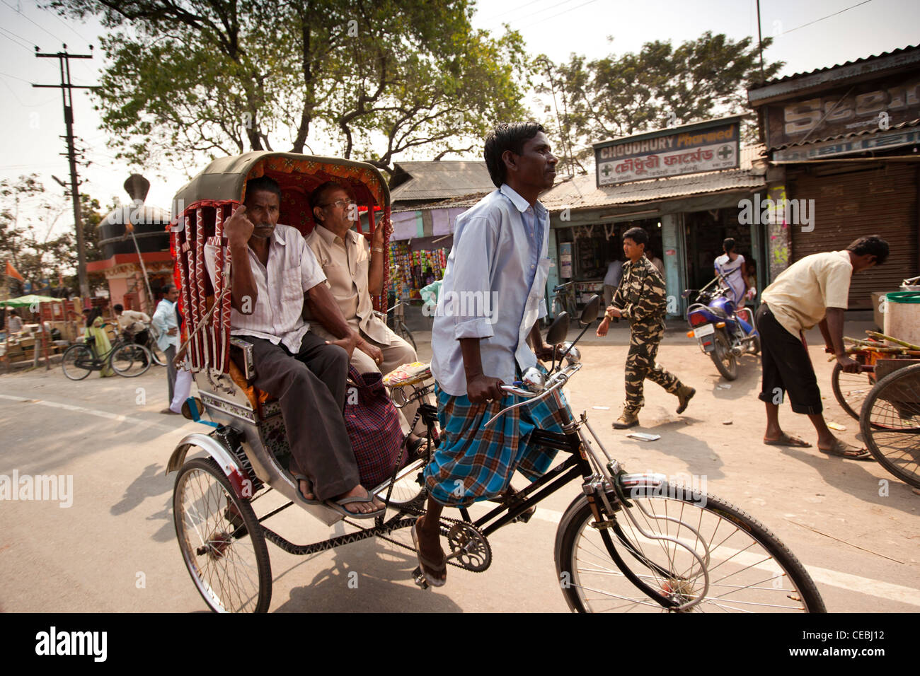 India, Assam, Tezpur, il trasporto di due passeggeri maschi in risciò ciclo Foto Stock