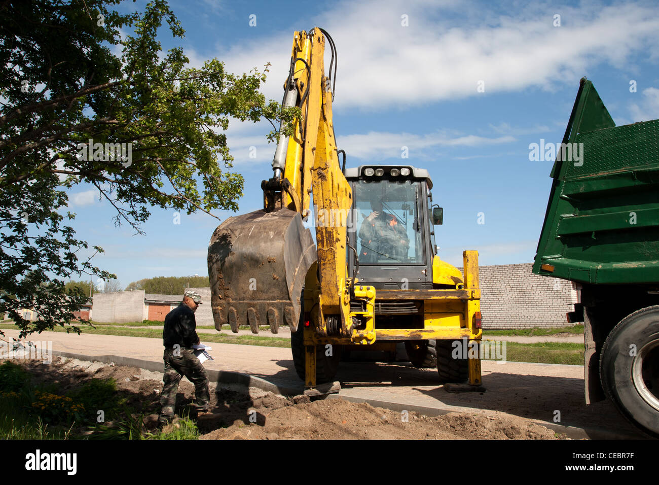 Nuova costruzione di strada con escavatore, camion e direttore dei lavori Foto Stock