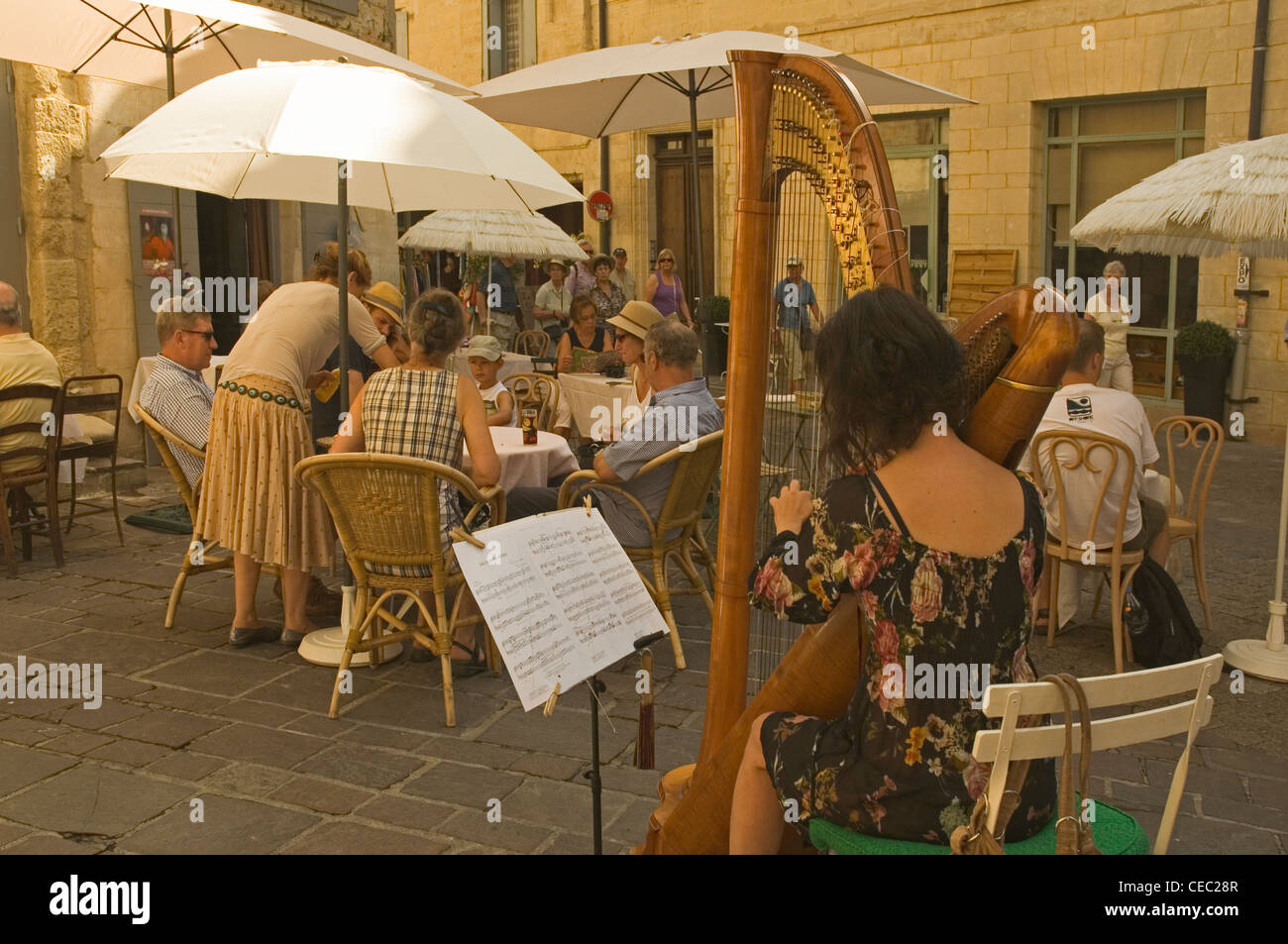 L'Europa, Francia, Uzes, piazza principale, Donna giocando un arpa presso una caffetteria locale Foto Stock