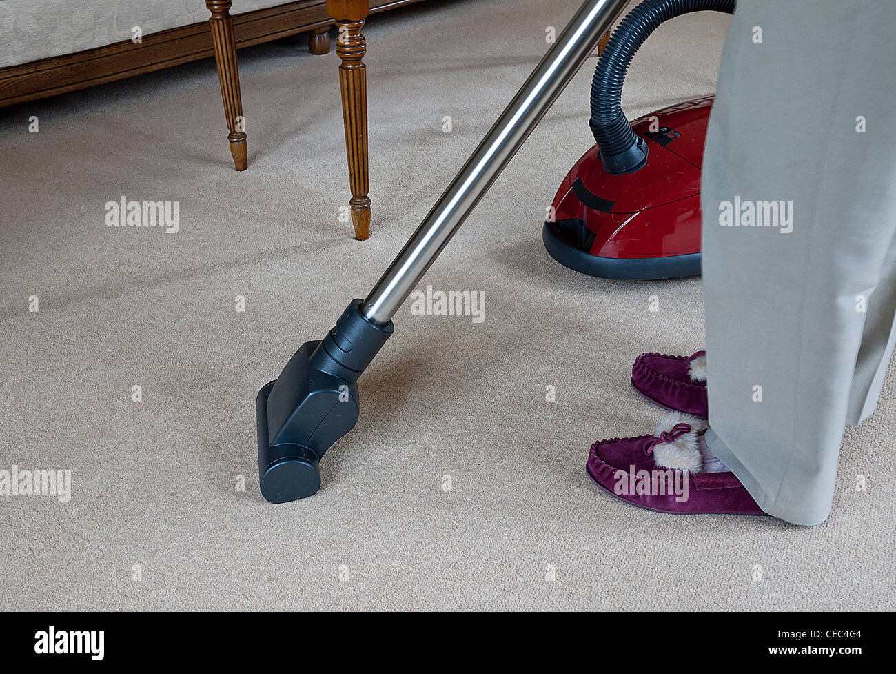 Signora a pulire un tappeto utilizzando un cilindro modello vac, UK. Foto Stock