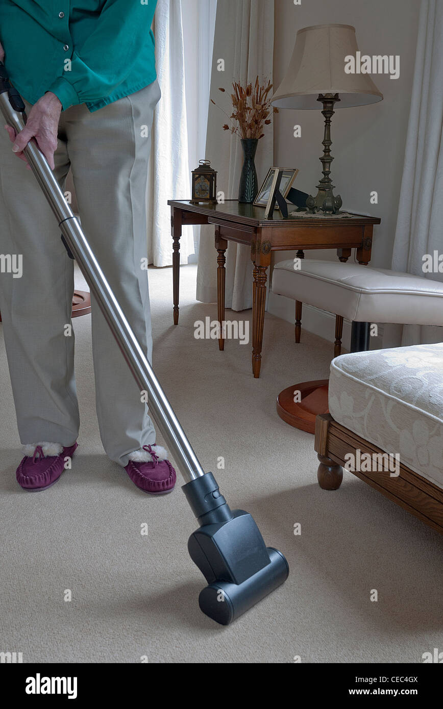 Signora a pulire un tappeto utilizzando un cilindro modello vac, UK. Foto Stock