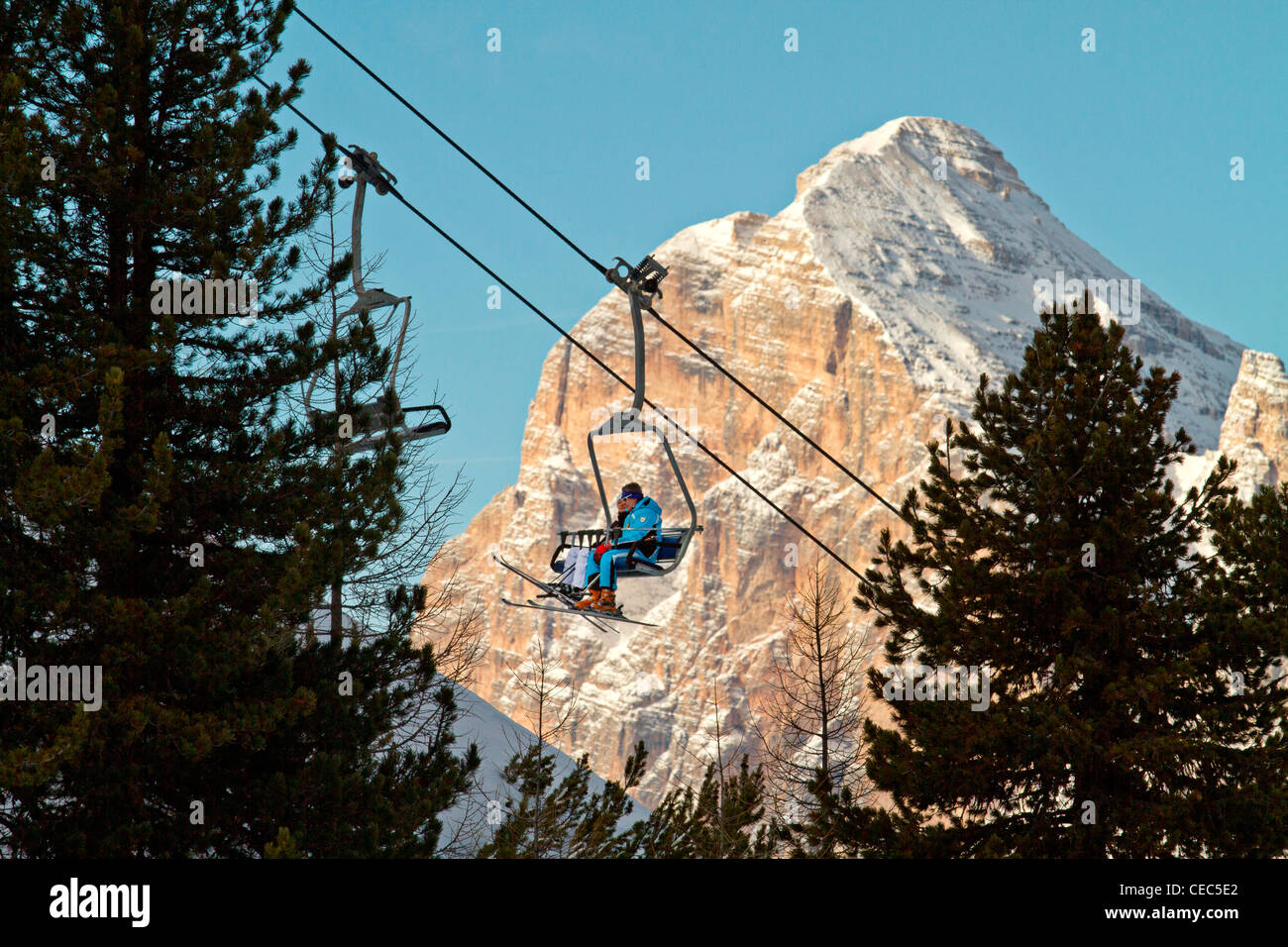 Gli sciatori su un impianto di risalita con la Tofana di Rozes in background, Faloria ski lift, Dolomiti, Cortina d;ampezzo, Italia Foto Stock