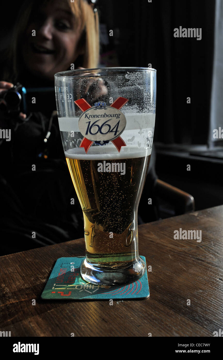 La pinta bicchiere di Kronenbourg 1664 birra lager in un pub Inglese UK bicchiere mezzo pieno o vuoto Foto Stock