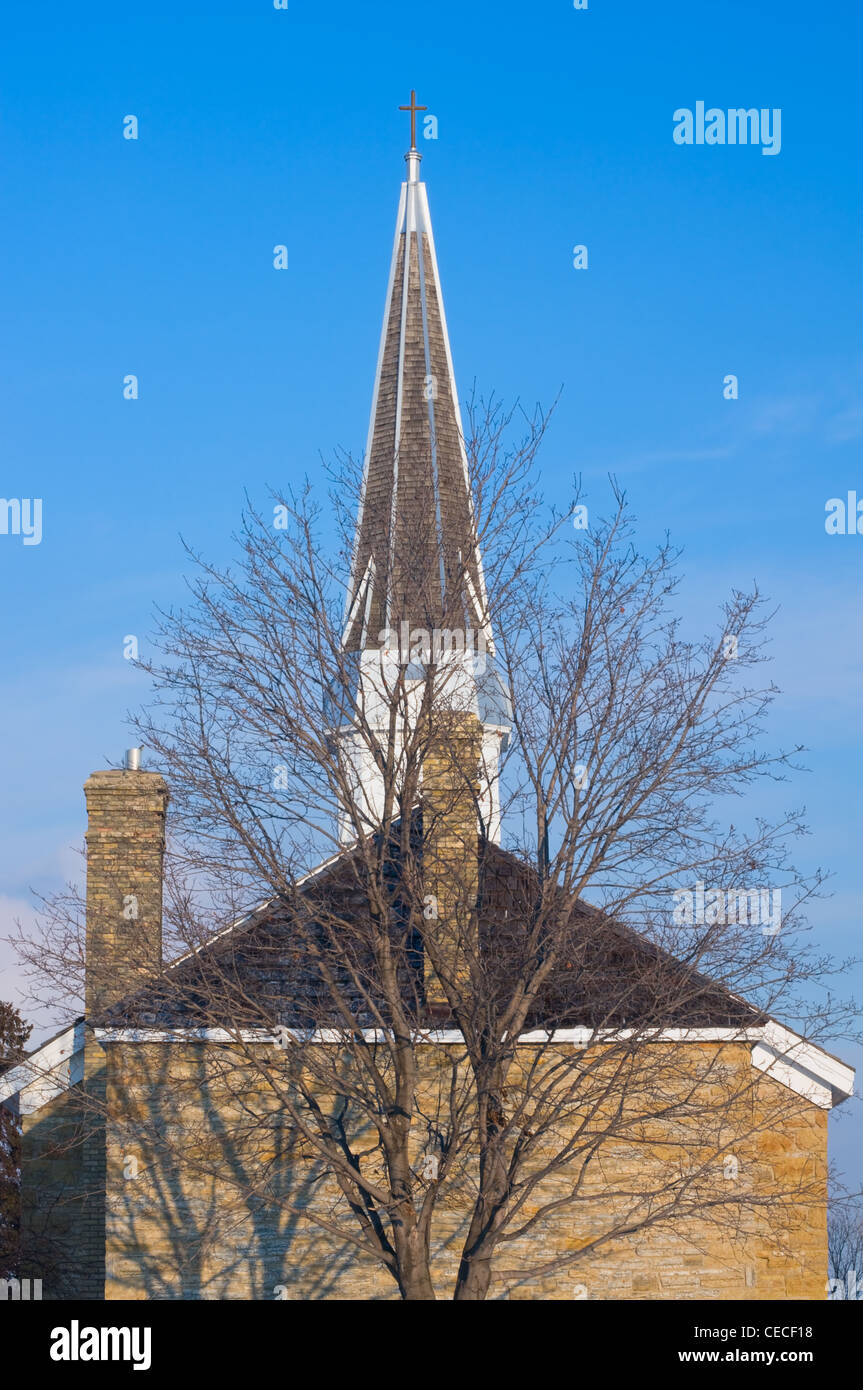 Chiesa di Saint Peters steeple e camini sotto i cieli blu in Mendota Minnesota Foto Stock