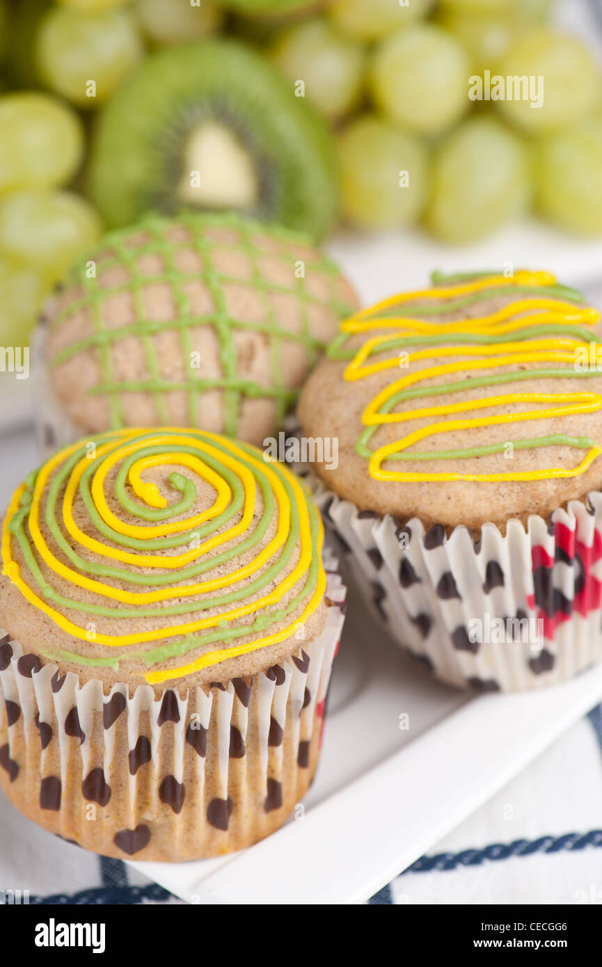 Tre i muffin su piastra bianca con uva e kiwi, il fuoco selettivo Foto Stock
