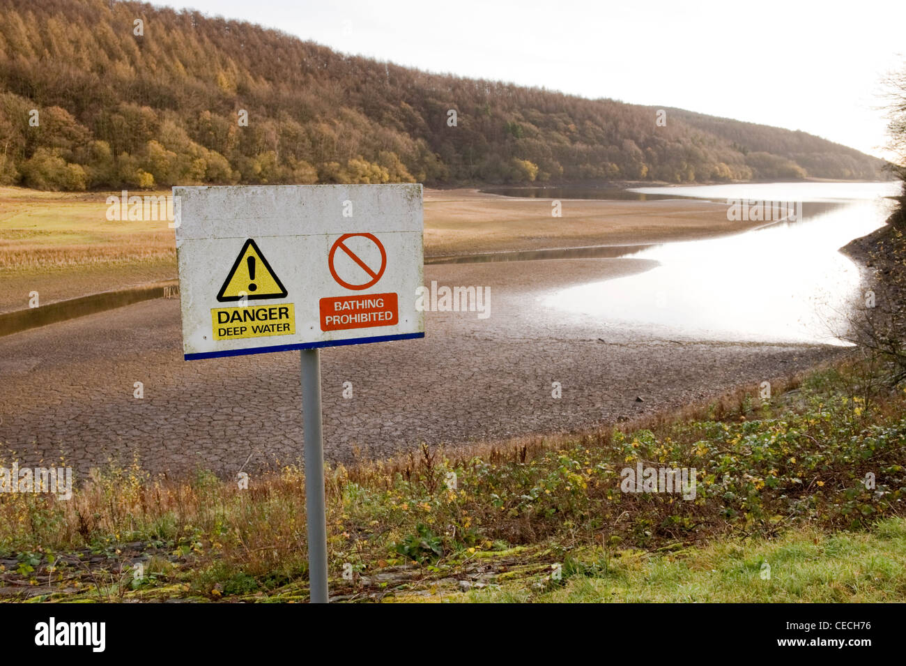 Basso livello dell'acqua dopo l'estate secca siccità & pericolo cartelli di avvertimento (deep acqua di balneazione) - ironia della sorte - Lindley serbatoio di legno, North Yorkshire, Inghilterra, Regno Unito. Foto Stock