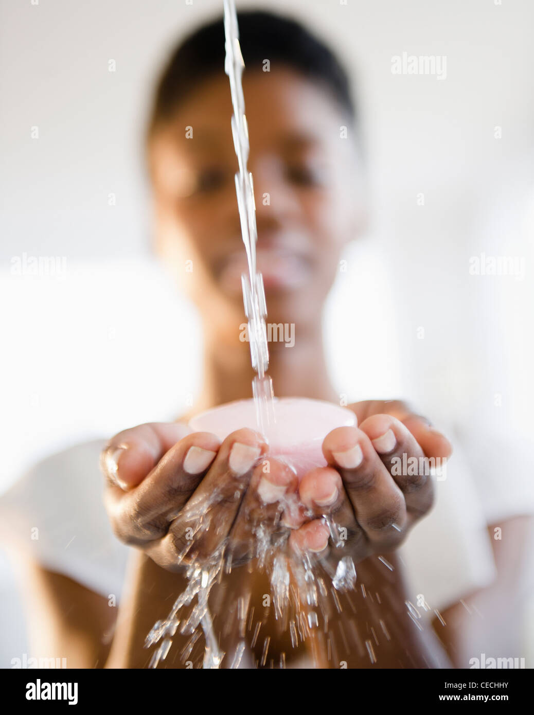 Spruzzi d'acqua su soap in Nero donna le mani Foto Stock