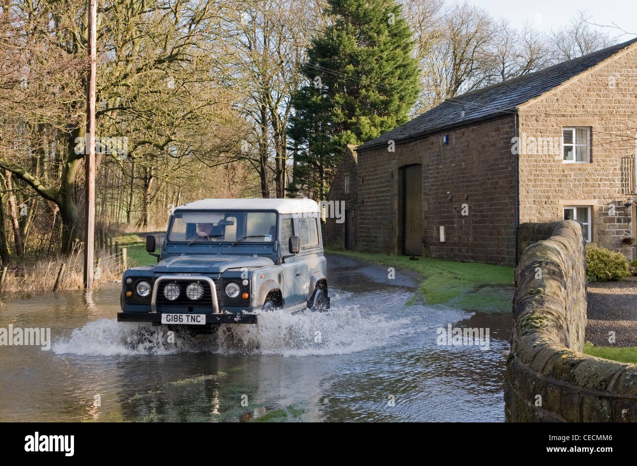 Allagamento - Land Rover Defender guidare & spruzzi attraverso le profonde acqua di inondazione su allagata strada rurale dopo la pioggia torrenziale - North Yorkshire, Inghilterra, Regno Unito Foto Stock