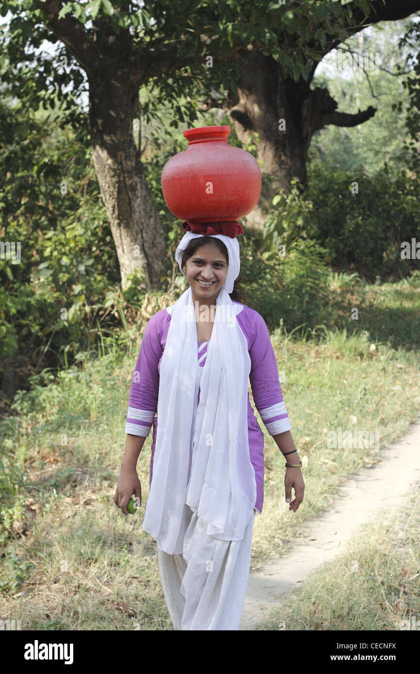 Donna indiana portando vasi d'acqua per riempire da ben ,gli abitanti del villaggio hanno a prendere l'acqua dalle sue fonti naturali. India Foto Stock
