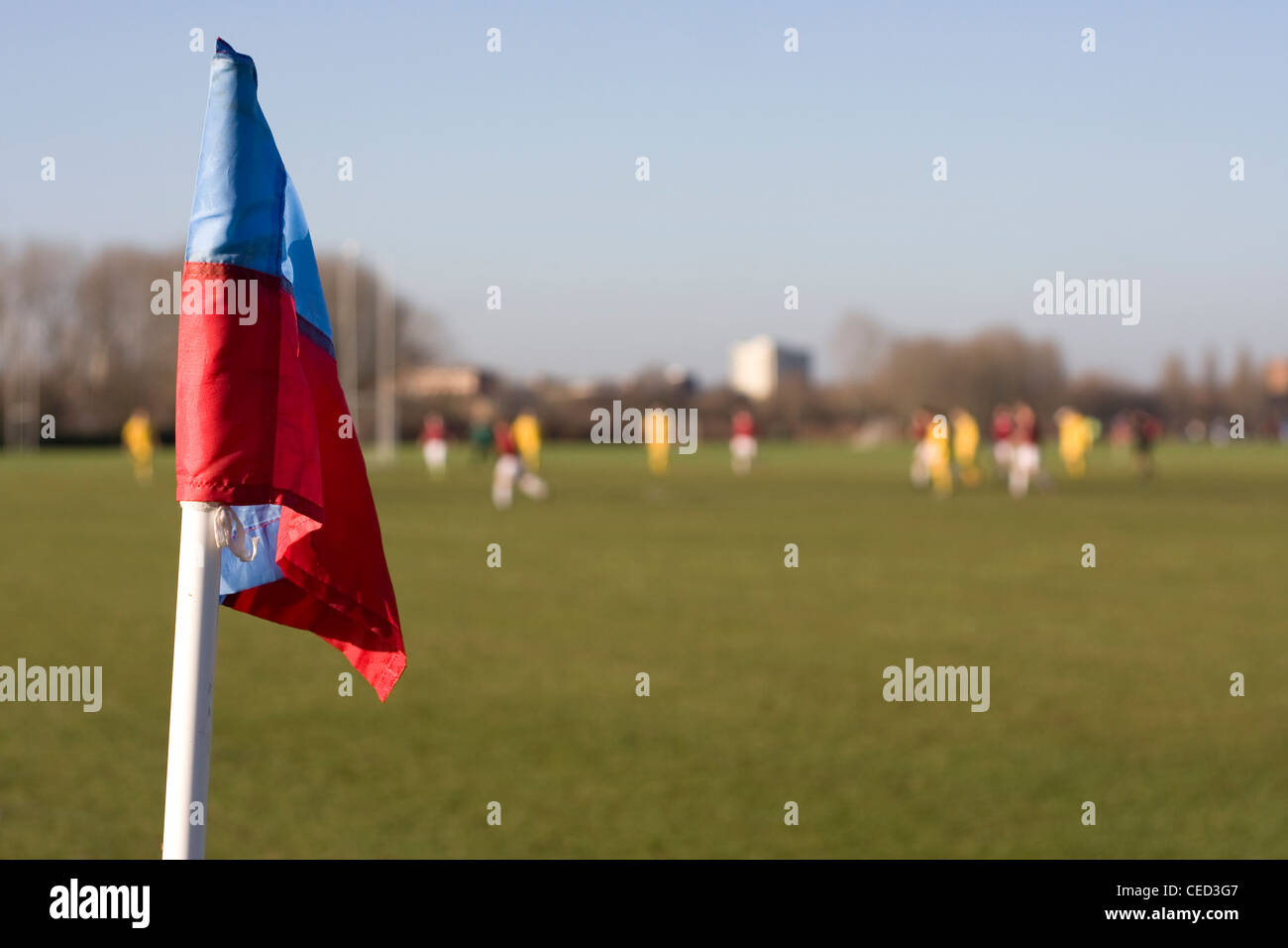 Il calcio partita di calcio con il blu e il rosso montante con bandiera, due squadre la riproduzione in background di paludi Hackney, Londra Foto Stock