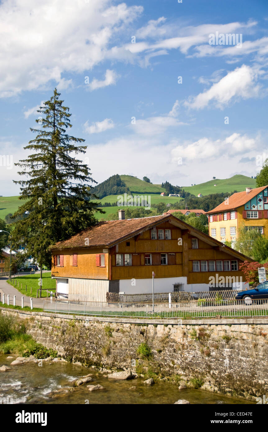 Vista verticale tipica di Swiss chalet in legno edificio accanto ad un flusso nella campagna svizzera in una giornata di sole. Foto Stock