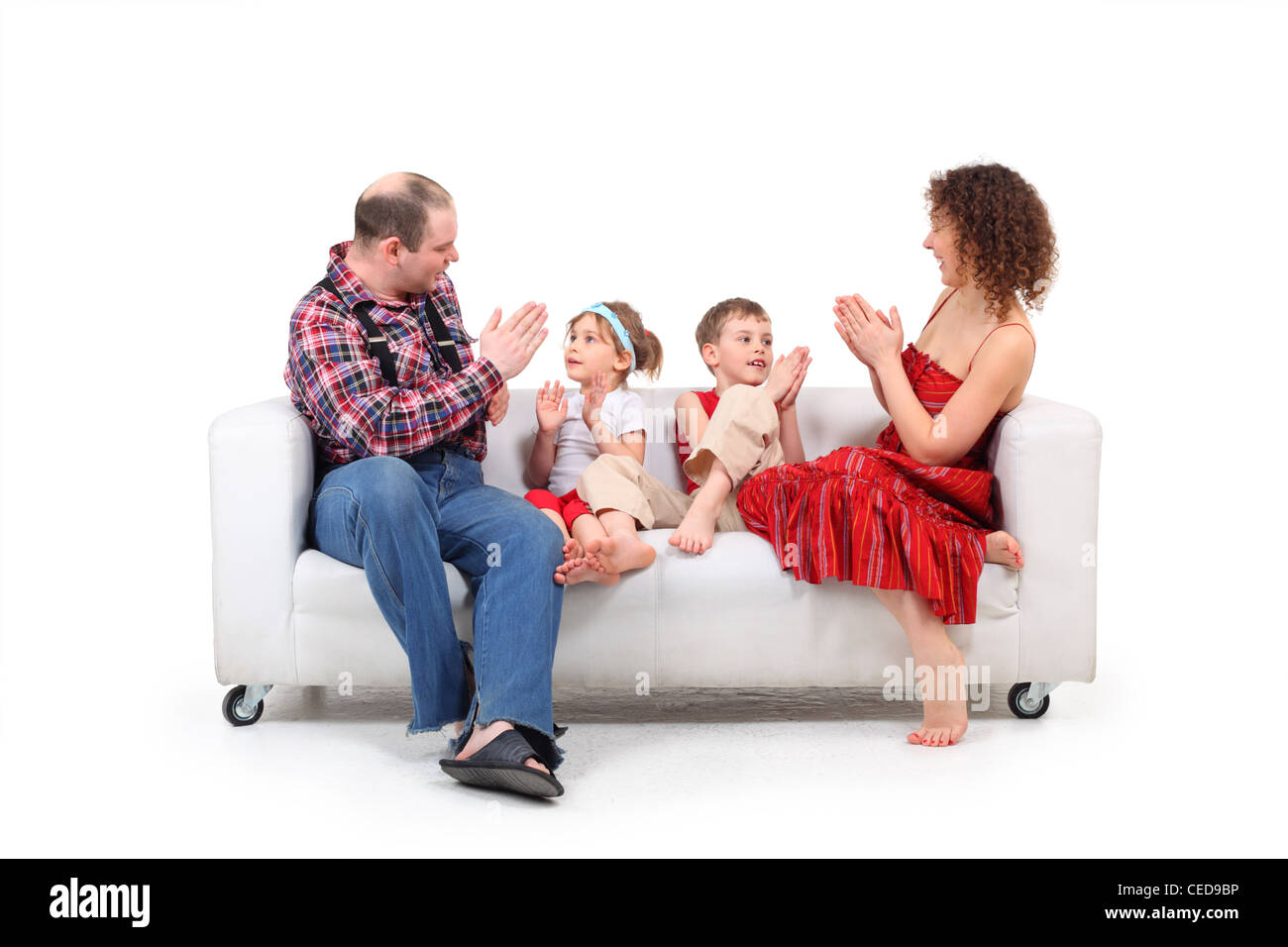 I genitori a giocare con i bambini su bianco divano in pelle Foto Stock