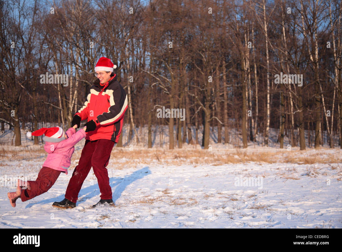 Padre ruotare la figlia in legno in inverno Foto Stock
