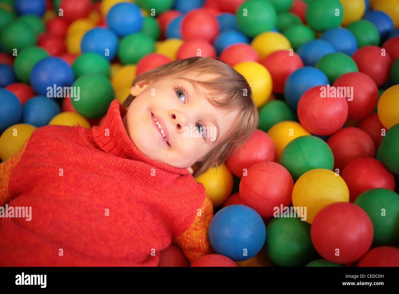 Bambina giace sul multi-colore di sfere di plastica Foto Stock