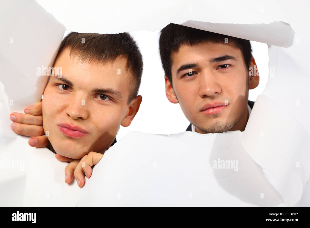 Due giovani uomini guardando fuori nel foro della carta Foto Stock