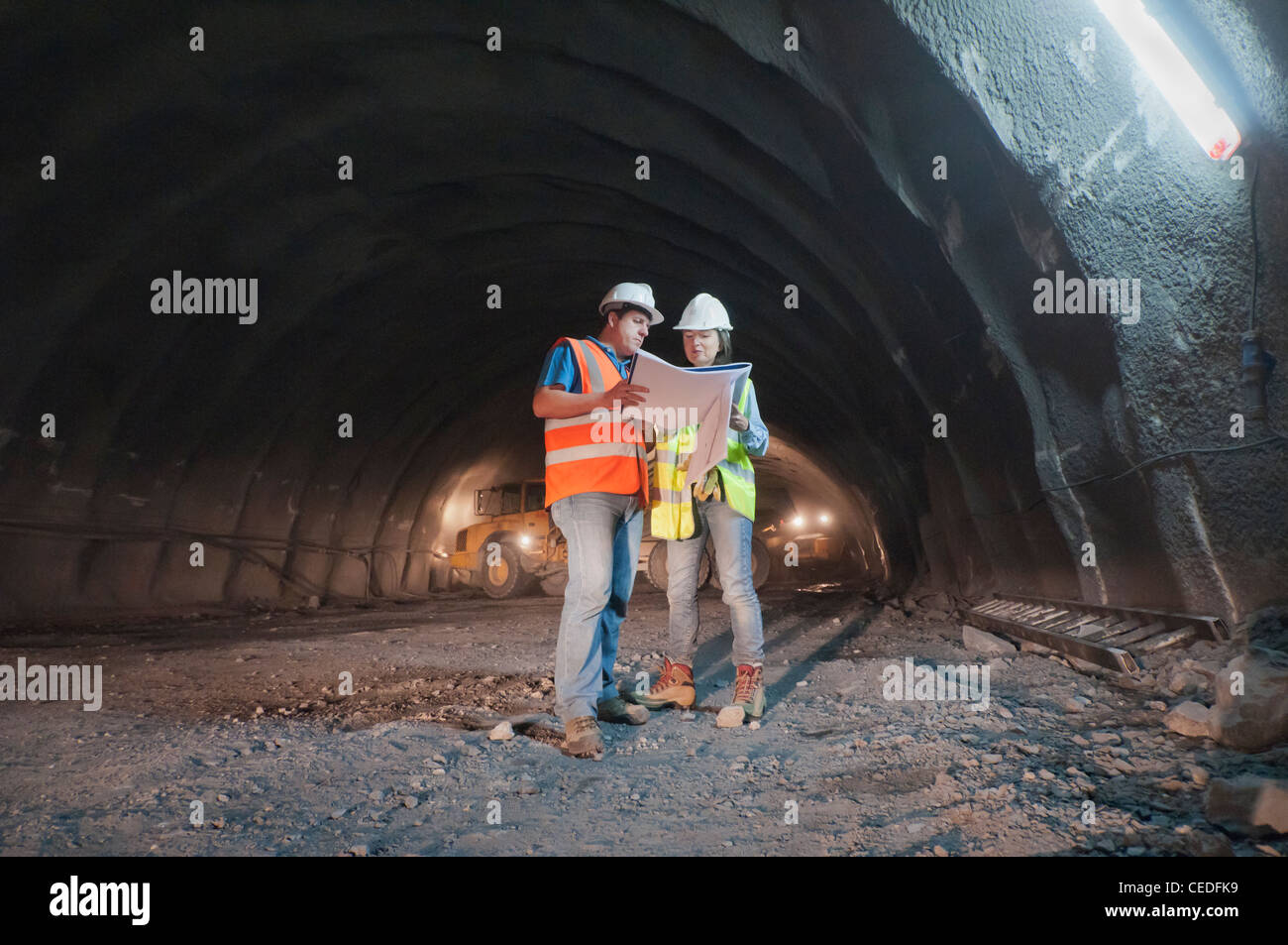 Lavoratori edili guardando blueprint nel tunnel Foto Stock