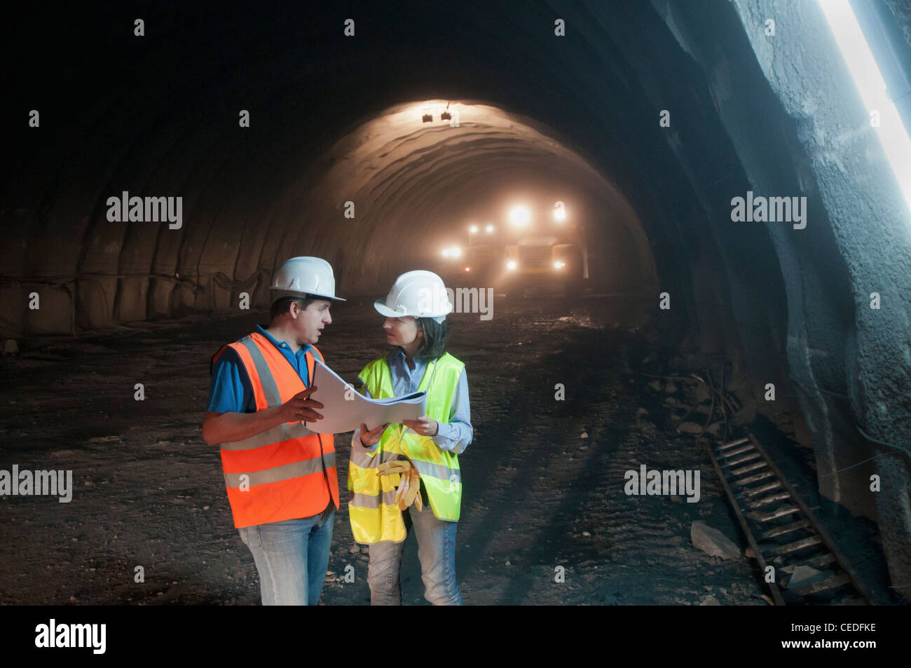 Lavoratori edili guardando blueprint nel tunnel Foto Stock