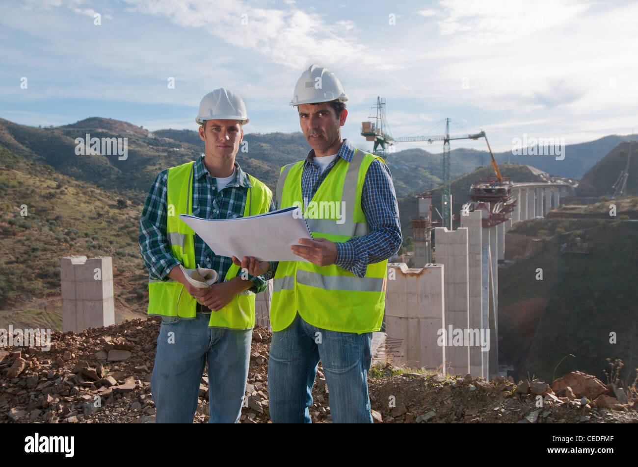 Lavoratori edili guardando blueprint al sito in costruzione Foto Stock