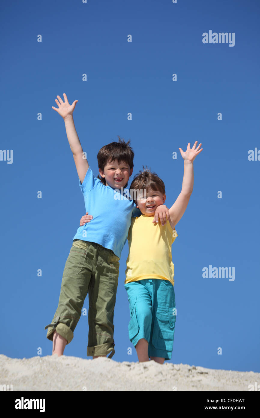 Due ragazzi di stare sulla sabbia e alzato le mani nel messaggio di saluto Foto Stock