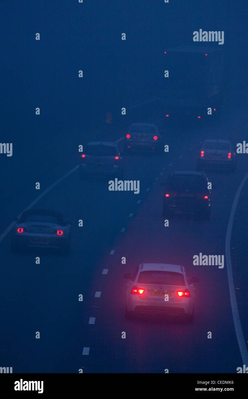 Vetture nella nebbia sulla strada in Inghilterra durante la notte Foto Stock