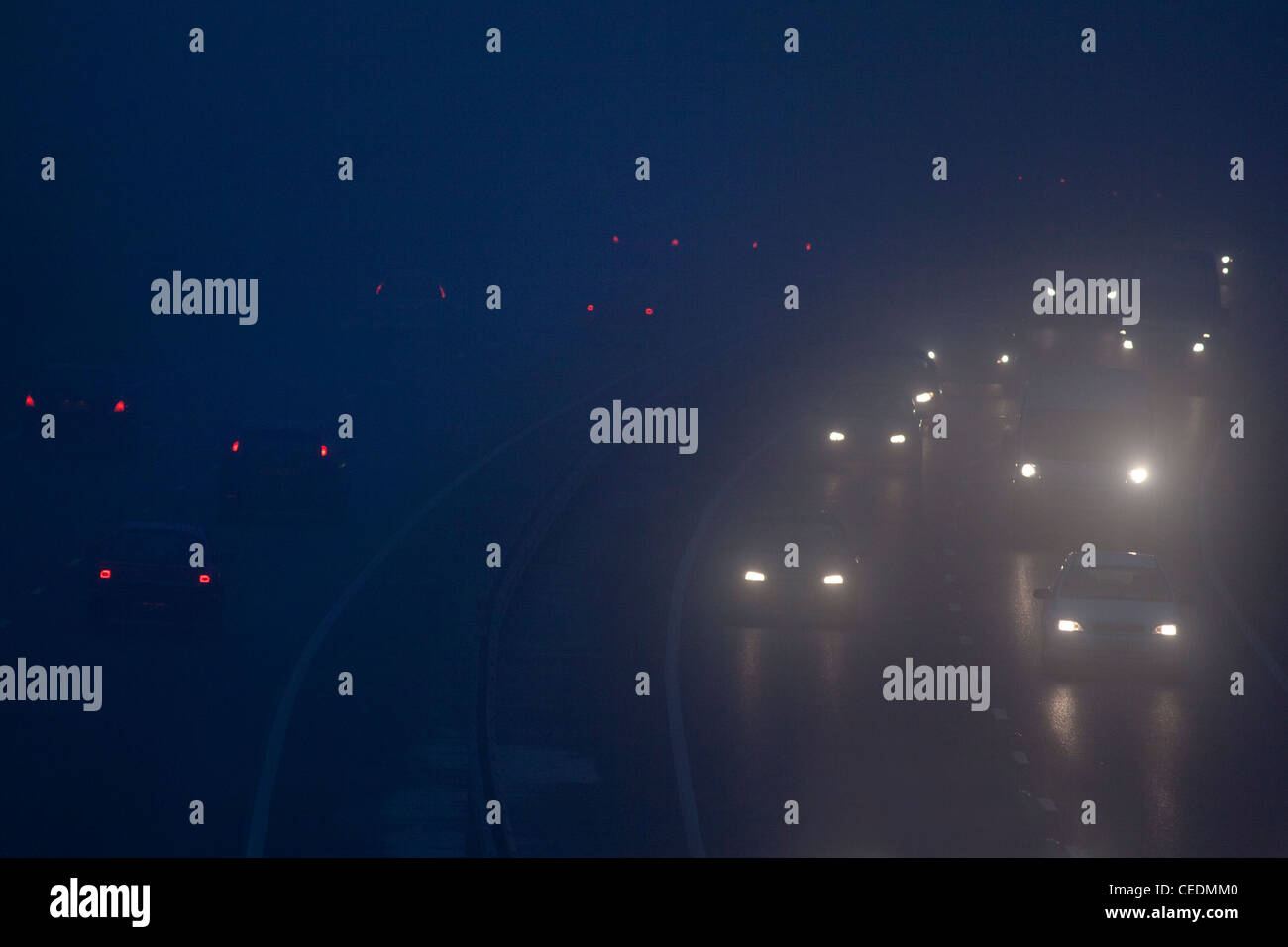 Vetture nella nebbia sulla strada in Inghilterra durante la notte Foto Stock