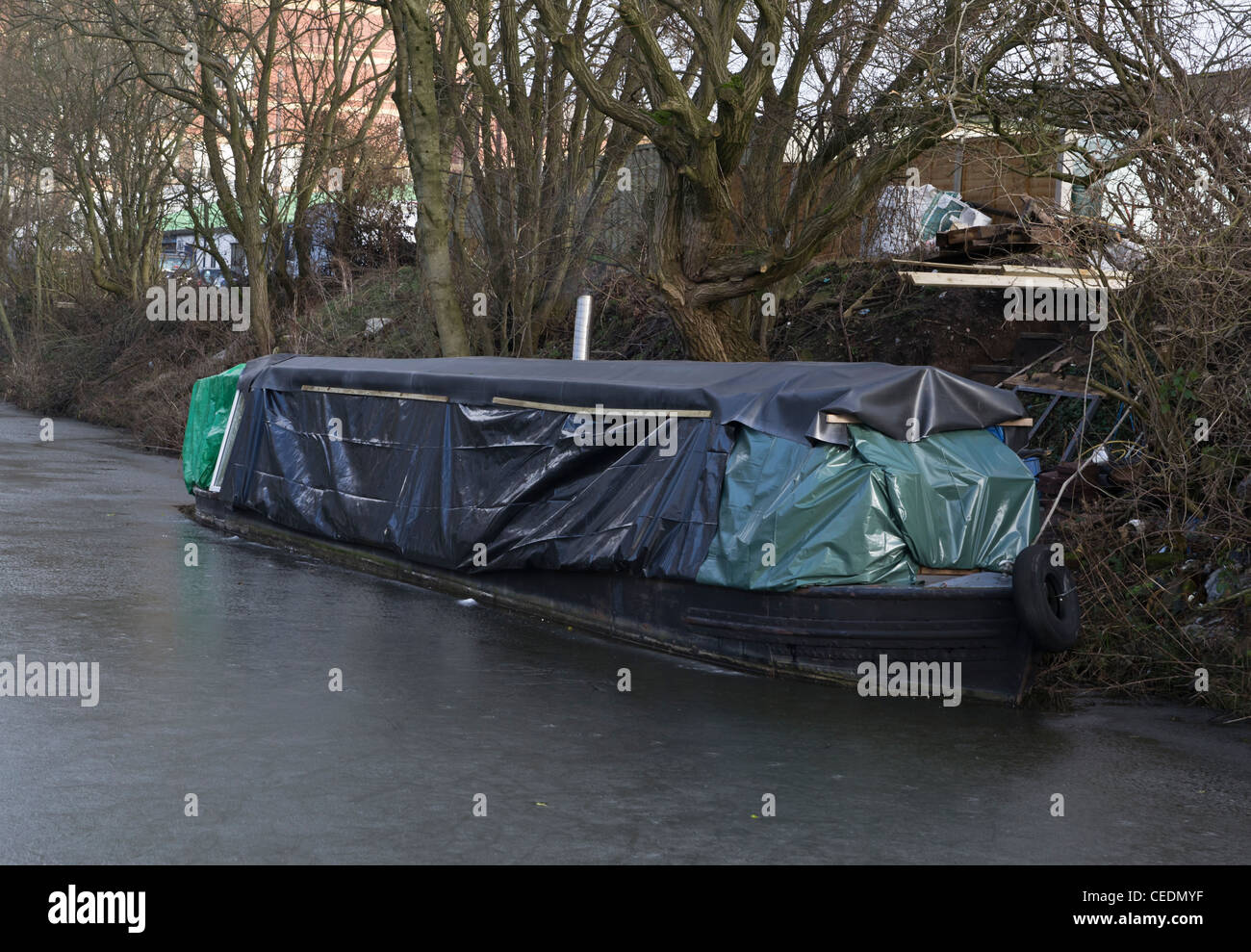 Canal Boat stretto coperto di teli di protezione su un canale congelati Foto Stock