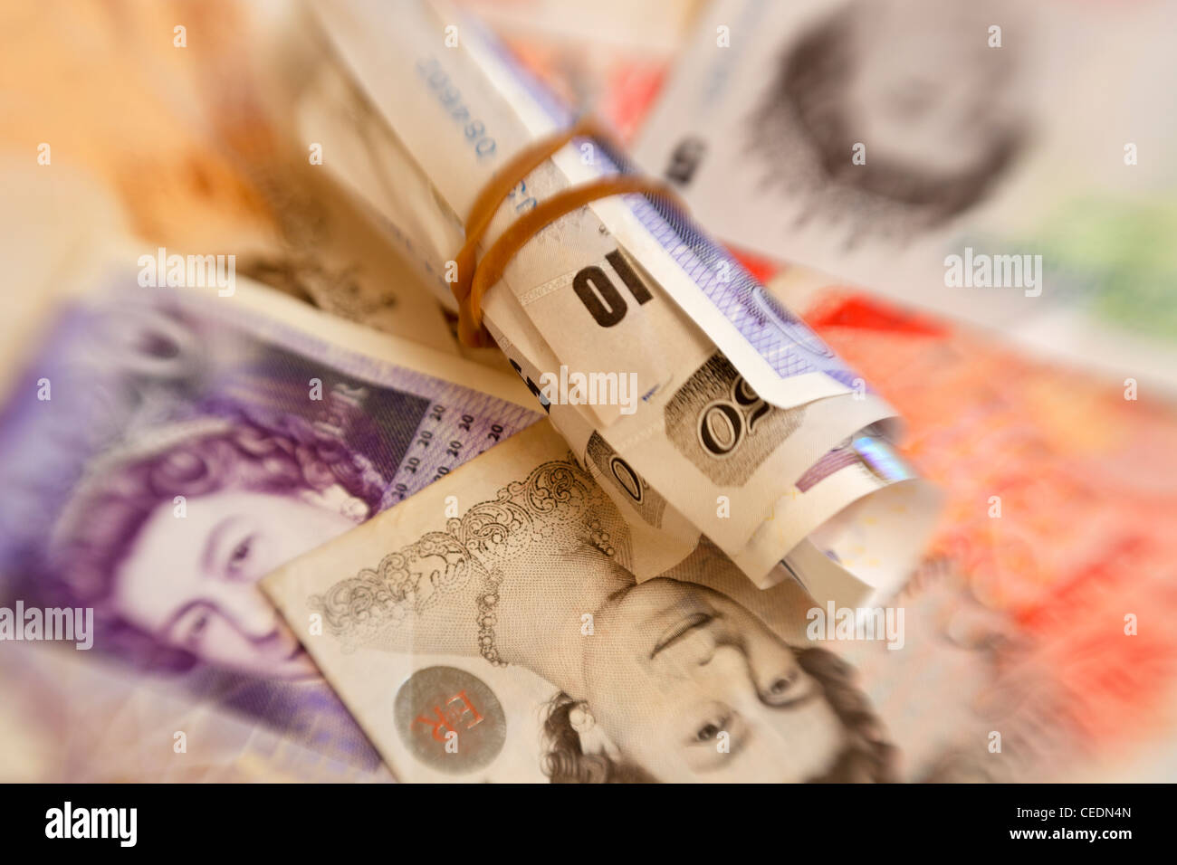 Un rotolo della sterlina inglese note poste sulla sommità della valuta inglese di importi differenti Foto Stock