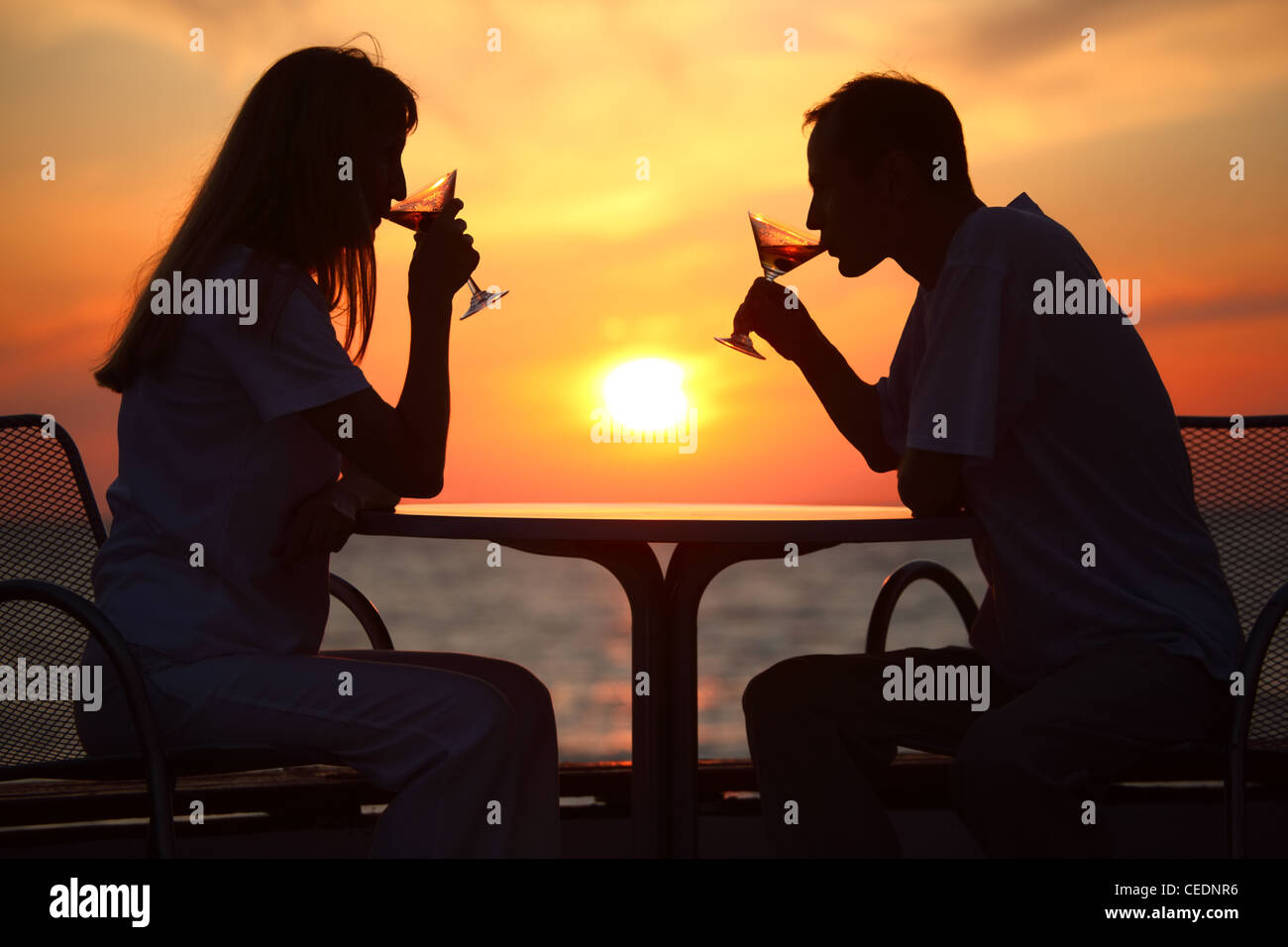 Donna e uomo di sagome sul tramonto dietro la tabella da Bere bicchieri Foto Stock