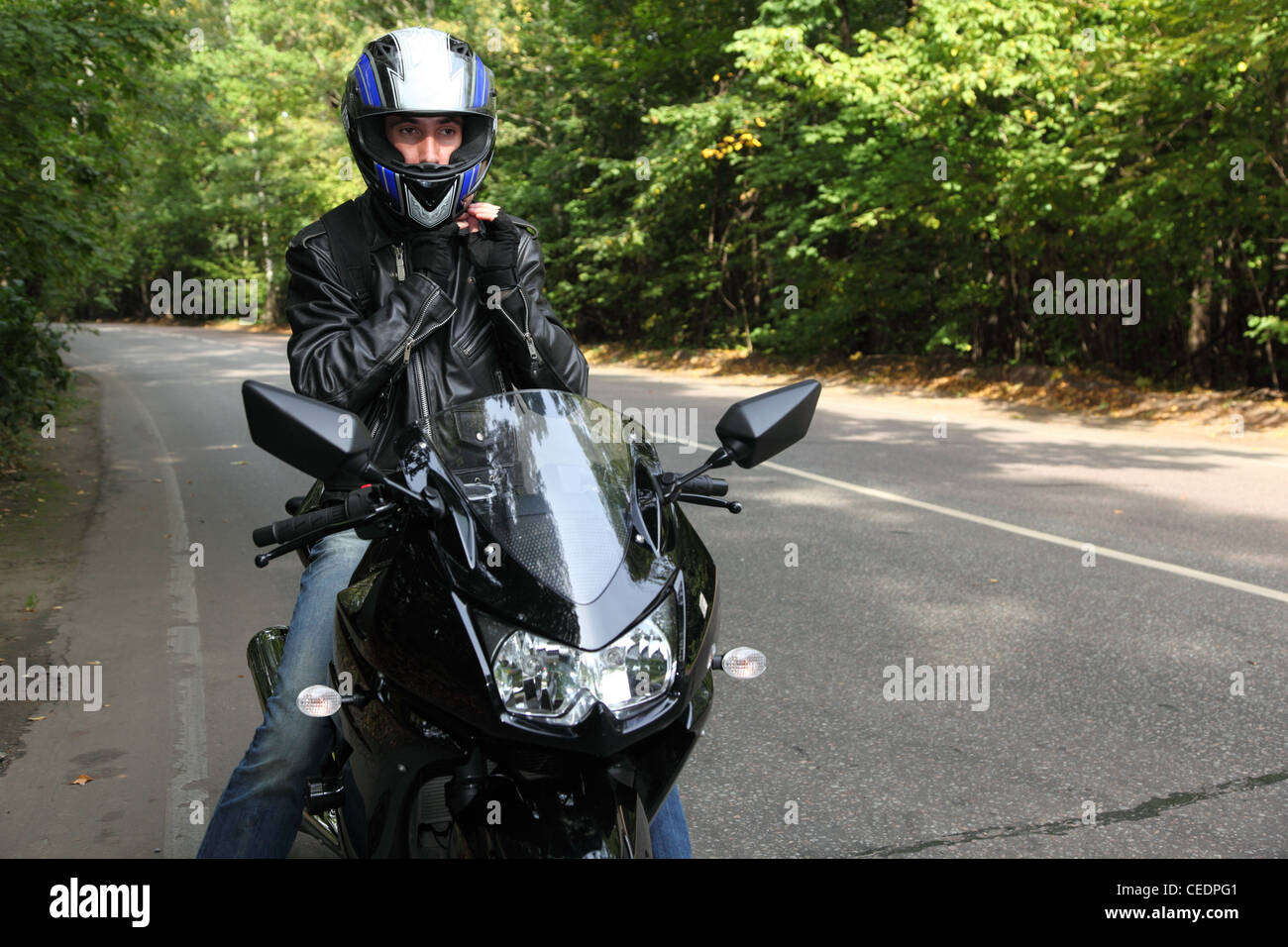 Motociclista permanente sulla strada Foto Stock