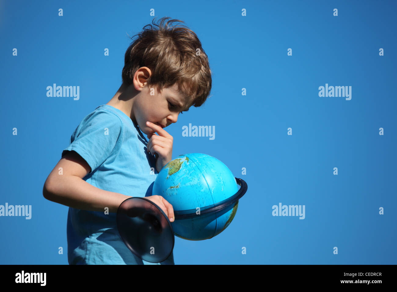 Ragazzo cerca sul globo terrestre contro sky Foto Stock